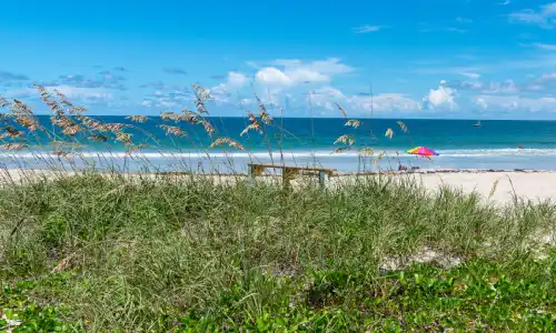 A sunny day at a Florida beach with a sun umbrella and lounge in the background.