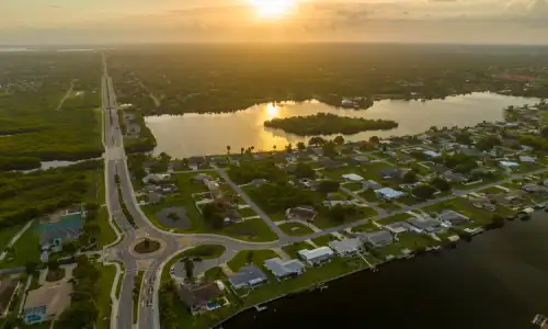 An aerial view of Port St. Lucie, featuring a lake and some marshland in the sunset.